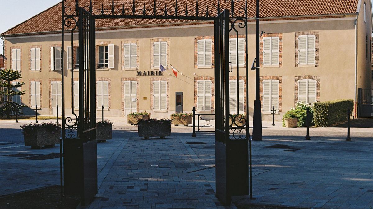 Grille ouverte devant la façade d’une mairie