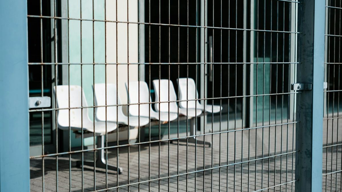 Sièges vides alignés derrière une grille métallique